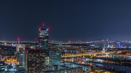 Fototapeta premium Aerial panoramic view over Vienna city with skyscrapers, historic buildings and a riverside promenade night timelapse in Austria.