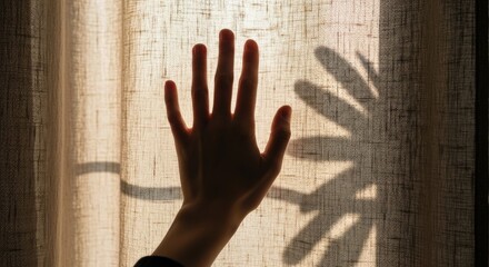 Silhouette of a hand touching a translucent curtain with a shadow cast by morning sunlight