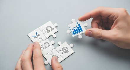Hands assembling puzzle pieces with business growth charts on a gray surface from above view