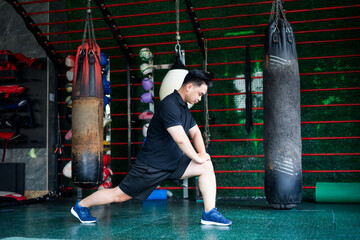 Asian man performs a stretching routine in a fitness center while preparing for boxing training...