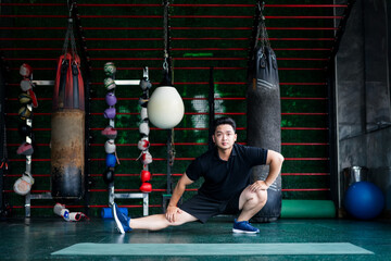 Flexibility training session with an Asian athlete in a boxing gym during the afternoon