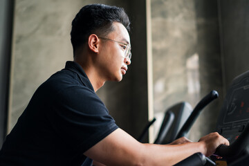 Focused young man exercising on an elliptical machine at a modern gym during the early morning hours