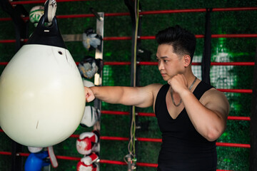 Man trains with a punching bag in a gym setting, demonstrating focus and dedication during a workout session
