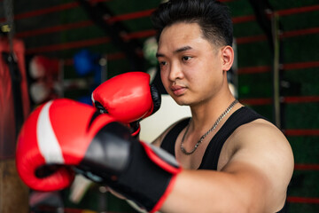 Young Asian male practicing boxing techniques indoors at a training facility during afternoon hours