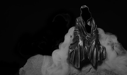 Ghost death figure sitting on rocks surrounded by swirling smoke and fog