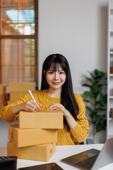 
Young woman small business owner writing on parcel box preparing package product fos her customer....