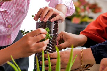 Hands Working Together On DIY Sustainable Gardening Project Using Recycled Plastic Containers