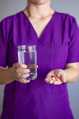 Doctor holding pills and glass of water recommending medication