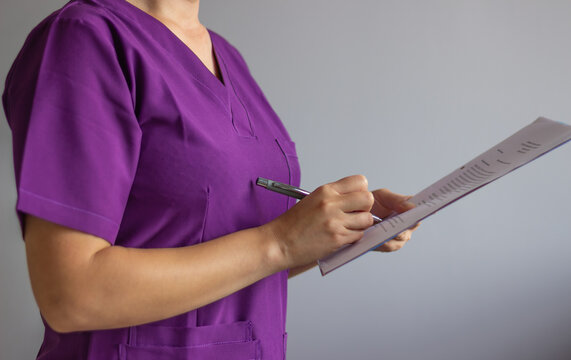 Female doctor writing medical report using pen and clipboard