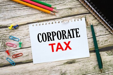 Corporate Tax. on a torn page from a notebook on a wooden table. view from above.