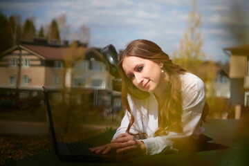 Fototapeta premium Young woman working on laptop outdoors in a residential neighborhood on a sunny day