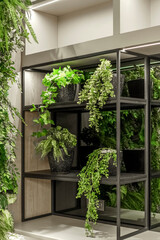 A black metal shelving unit decorated with various artificial potted plants, including fern and pothos, creating a modern biophilic interior style.