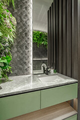 Modern bathroom vanity with a green cabinet, grey marble top, and a lush vertical garden. Biophilic...