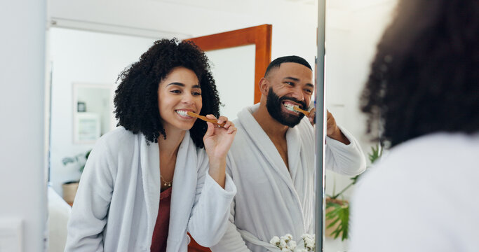 Couple, brushing teeth or mirror in bathroom for dental care, wellness or morning in home. Man, woman or oral hygiene with reflection or toothbrush for routine, cleaning mouth or gum health in house