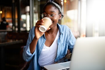Woman drinking coffee in cafe while working on laptop remote work lifestyle photo