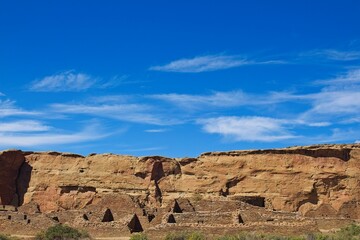 Part of Chaco Canyon Pueblo with a cliff and sky with clouds in the background, New Mexico.