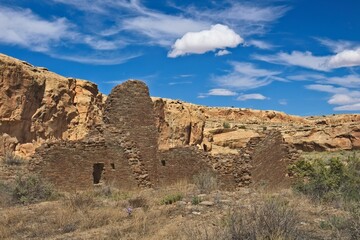 Part of Chaco Canyon Pueblo with a cliff and sky with clouds in the background, New Mexico.