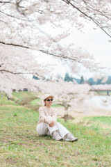 Woman tourist sightseeing Sakura Cherry Blossom in Spring. Happy traveler travel near Hinokinai...