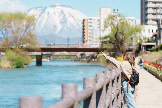 Woman tourist sightseeing Iwate mountain and Kitakami river with flowers in Spring, happy traveler travel in Morioka city, Iwate prefecture, Japan. famous Landmark Travel and Vacation destination