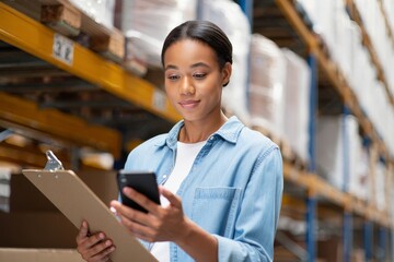 Woman worker using smartphone in warehouse for inventory management and logistics