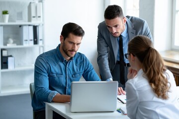 Obraz premium Business team collaboration meeting in office analyzing data on laptop teamwork success