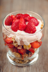 Greek yogurt, granola and strawberry on the rustic background. Selective focus.