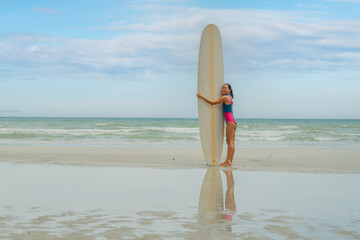 Asian play surf alone on the summer beach. Solo outdoor activity on holiday