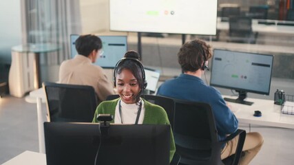 Confident African American female call center agent communicates with clients using headset and computer. She offers professional tech support at a modern office desk, smiling diverse office - Powered by Adobe