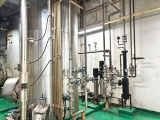 Interior of an industrial plant with stainless steel tanks, pipelines, and mechanical equipment....