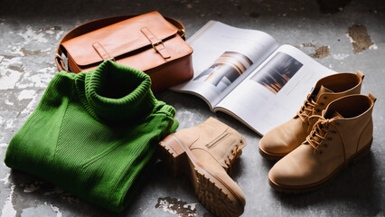 Casual Style Still Life - Turtleneck, Boots, and Magazine, A curated still life composition featuring a folded green turtleneck sweater, a pair of tan boots, and an open magazine on a concrete floor.