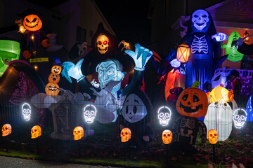 Halloween setup with illuminated inflatable characters like Dracula, skeletons, and pumpkins...