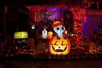 Glowing outdoor decorations with ghost cat in the pumpkin on the background of ghosts, graves and...