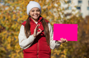 teenager girl suggest something on paper with copy space. autumn girl make a suggestion. girl...