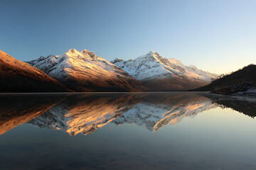 Majestic Mountain Range Reflected in Tranquil Lake at Sunrise  Scenic Nature Landscape with Calm Water and Mirror Like Reflection

