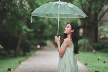 Teenage girl holding clear umbrella serene park path portrait nature side view reflection