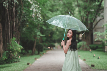 Teenage girl with umbrella strolling through lush park nature scene peaceful environment