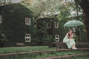 Teenage girl with umbrella in lush green garden nature scene serene viewpoint
