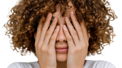 Close-up of a person with curly hair covering their face with hands, expressing emotions like fear or anxiety.