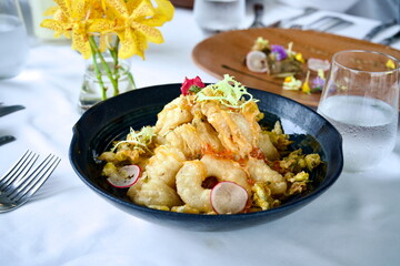 Gourmet Japanese Tempura Seafood Dish with Ikura and Vegetables, Served in a Black Ceramic Bowl on White Tablecloth, Elegant Fine Dining Plating with Flower Decoration and Glass of Water