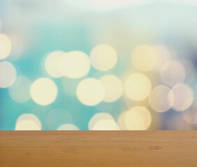 Empty brown wooden table surface for product placement with bokeh from indoor lighting in background, Blue and yellow circles spread on green and purple surface