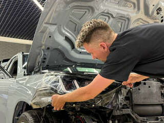A car wrapping specialist applies a polyurethane film to the car. Detailer smoothes PPF. Car...