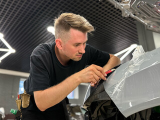 A car wrapping specialist applies a polyurethane film to the car. Detailer smoothes PPF. Car...