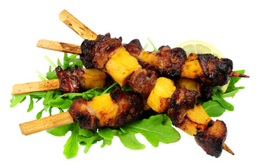 Grilled pork and pineapple Hawaiian skewers with wild rocket salad leaves isolated on a white...