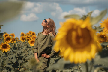 A girl in a pink skirt and a white T-shirt walks through a field of blooming yellow sunflowers. A woman dances, rejoices, smiles, enjoys life, warmth, summer, the sun. High quality FullHD footage