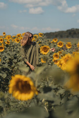 A girl in a pink skirt and a white T-shirt walks through a field of blooming yellow sunflowers. A woman dances, rejoices, smiles, enjoys life, warmth, summer, the sun. High quality FullHD footage