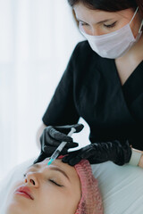 aesthetic professional performing an injection procedure in the glabellar region. Beauty treatment