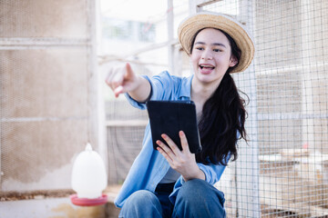 Young generation z woman scientist in agricultural farm education using tablet outdoor with happy expression pointing at something in cage