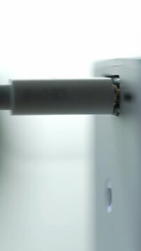 A black USB-C cable's silver-tipped connector glides smoothly into a minimalist port on a sleek, white electronic device in a high-key MCU, with very shallow depth of field and soft bokeh, slow