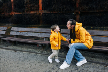 Mother talking to son in yellow raincoats outside