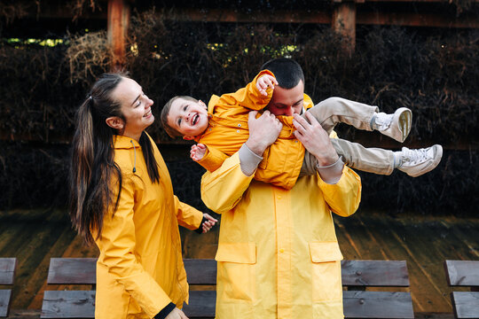 Smiling parents playing with child in yellow jackets